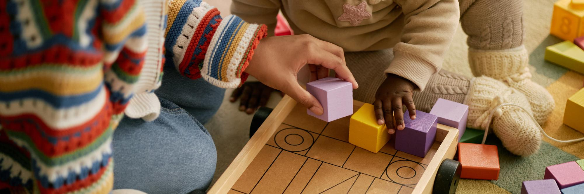 Toddlers playing with wooden building blocks at Lovely Child Home Daycare