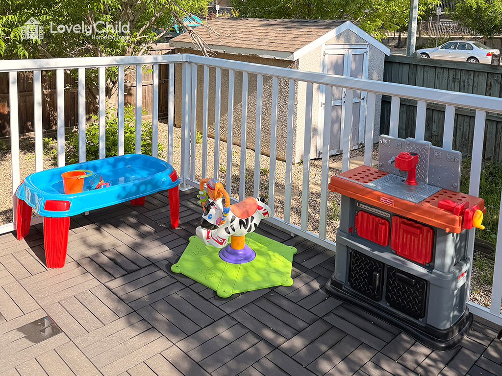 Outdoor play deck with sensory table and ride-on toys
